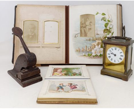 A carriage clock, in a brass and glass case, 15 cm high, two Victorian photograph albums, and a punch (box)