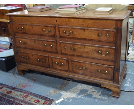 A George III cross-banded oak mule chest, the hinged top over four dummy drawer fronts and three drawers, with brass fittings