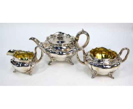 A William IV silver three-piece tea service of lobed and compressed form, flower finial and foliate feet, naturalistic crabst