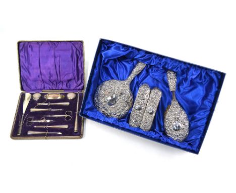 A cased manicure set with loaded silver handles, Birmingham 1919 to/w an embossed silver four piece brush set, Birmingham 191