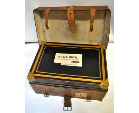 A japanned metal and gilt travelling trunk in tan leather case with travel label and label to top for Rev. H. M. Sanders c/o 
