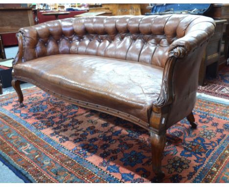 A Victorian walnut framed button upholstered brown leather small sofa, raised on moulded cabriole front legs, to ceramic cast