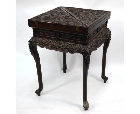 An antique Chinese hardwood envelope card table, moulded and relief carved overall with dragons, flaming pearl and cherry blo