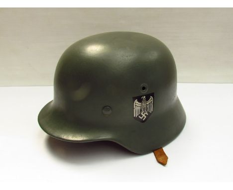 A German design M40 helmet with later green paintwork and decals, brown leather liner and chinstrap 