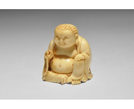 19th century AD. A carved ivory figurine of Buddha wearing an open-fronted jacket, sitting with the left hand on the raised l