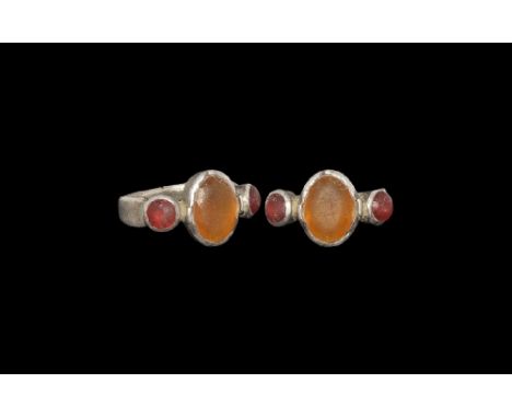 13th-15th century AD. A flat-section silver hoop with bezel formed as three discoid cells, yellow and red glass cabochon inse