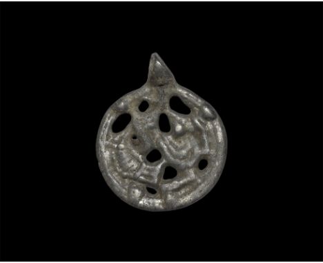 10th-11th century AD. A flat-section discoid openwork pendant with ribbed border, enmeshed beast within. From an old Munich c