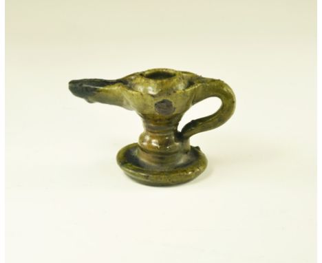 An undated archaistic green-glazed ceramic oil lamp with discoid base, balustered stem, conical chamber with open-topped spou