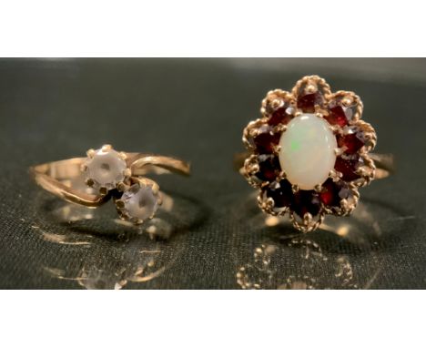 An oval opal and red garnet cluster ring, creamy white opal cabochon surrounded by ten round deep red garnets, 9ct gold shank