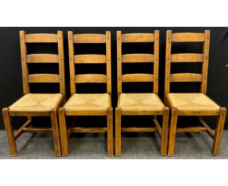 A set of four Griffiths style solid oak ladder back dining chairs, drop-in rush seats, pegged construction, 108.5cm high x 46