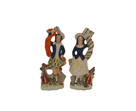 A pair of Staffordshire portrait figures of Highland dancers, dressed in Scottish attire each with a stringed instrument. Cir