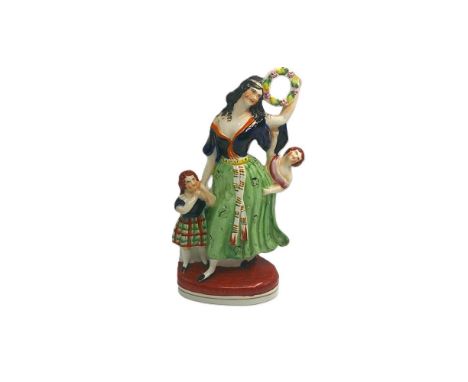 A Staffordshire portrait figure of a lady dancing holding a floral hoop, with a child either side, Circa 1860, size 29.5cm hi
