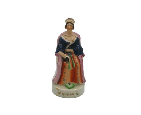 A Staffordshire Alpha portrait figure of Queen Victoria, seated on a chair holding a book in her hand and her foot resting on