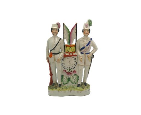 A Staffordshire portrait figure of two soldiers standing either side of a clock, a bugle, a drum and flags, Titled V Rifles i
