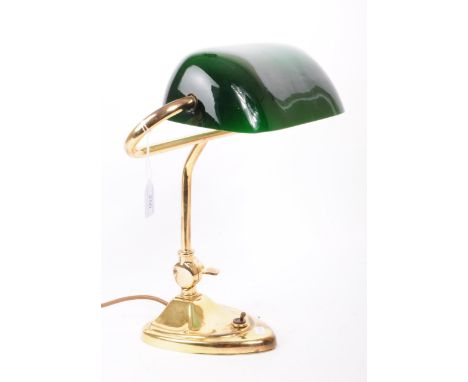A vintage 20th century bankers lamp, with a green glass shade and brass art nouveau style stand with toggle switch to the bas