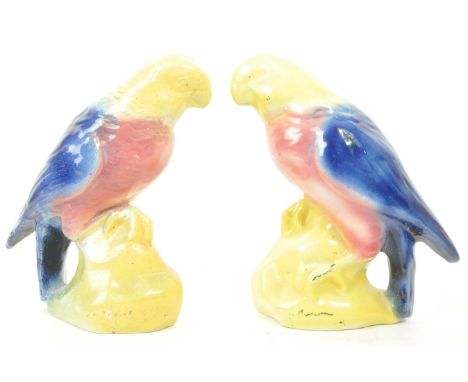 A pair of 19th century Victorian ceramic bird parrot figurines, with a yellow, pink and blue glaze. Largest measuring approx.