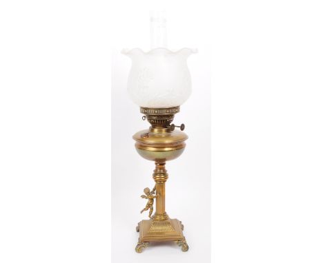 Early 20th century brass columnar oil lamp mounted on four scrolled feat with a brass cherub figure to the column stand. Feat
