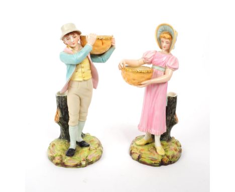 Royal Worcester - Two late 19th century porcelain figurines / spill vases, in the manner of Kate Greenaway. Depicting a lady 