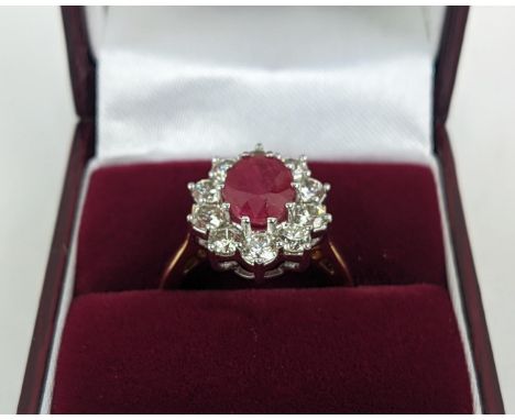 AN 18CT GOLD RUBY AND DIAMOND CLUSTER RING, the central mixed cut ruby of approximately 2.25 carats, surrounded by ten round 