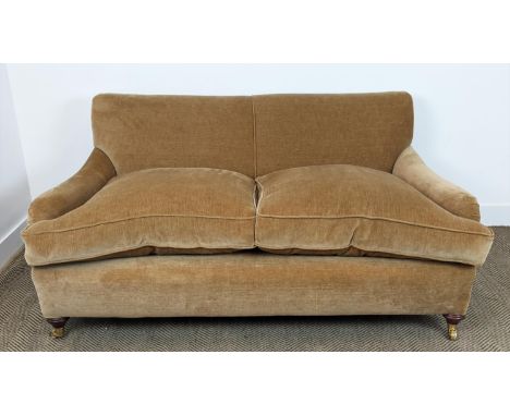 HOWARD STYLE SOFA, tan coloured velvet on brass castors, 77cm H x 165cm W x 97cm D. 