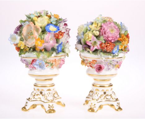 A ROYAL CROWN DERBY PORCELAIN GARNITURE, comprising a pair of floral entrusted urns, raised on four scroll feet, painted puce