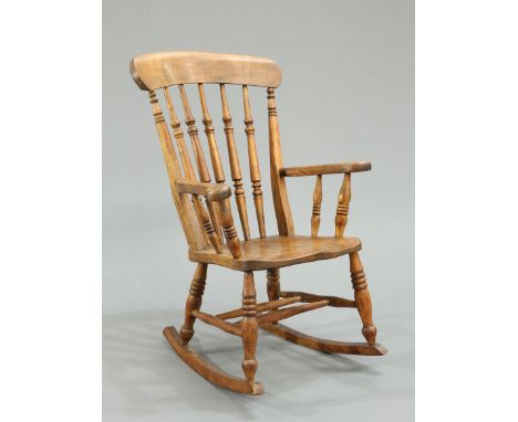 A 19TH CENTURY ELM AND BEECH ROCKING CHAIR, with turned spindle back and ring turned baluster legs.&nbsp;