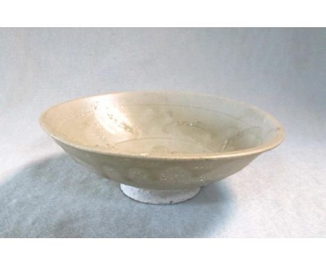 A Song dynasty shallow dish from a shipwreck, carved with stylised waves, the pale olive glaze covering a whitish body,  15.7