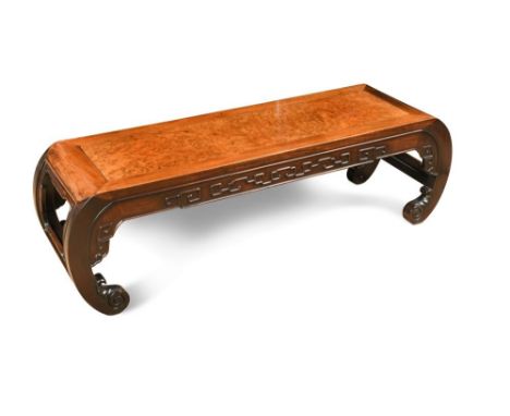 A Chinese hardwood Opium table, with a burr elm inset panel top, curved ends with carved decoration to the frieze, on scroll 