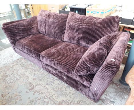 A purple coloured velour three seater sofa 