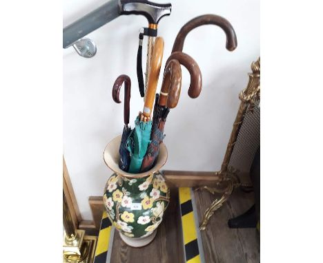 A vase/stick stand with walking sticks and umbrellas 