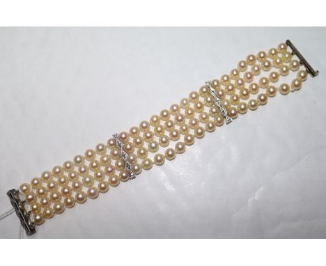 A triple strand cultured pearl bracelet with diamond set white metal clasp and spacers, 19cm.