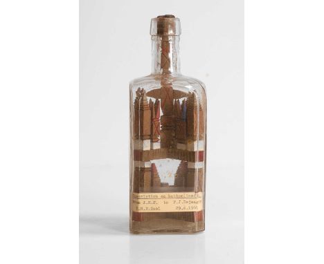 A Boer War prisoner-of-war 'whimsey' art in a bottle, c.1901, the square-form glass bottle housing a carved wood folk art puz