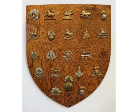 26 Infantry cap badges mounted on shield.   Good selection beautifully mounted on varnished wooden shield, each with gold ill