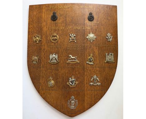 16 Cavalry cap badges mounted on shield.   Good selection beautifully mounted on varnished wooden shield, each with gold illu
