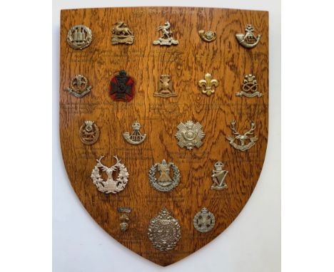 20 Infantry cap badges mounted on shield.   Good selection beautifully mounted on varnished wooden shield, each with gold ill