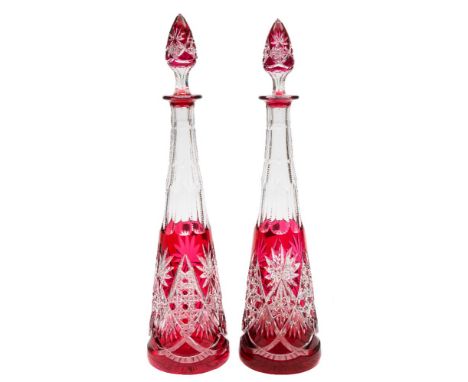 A pair of ruby overlaid clear glass decanters and stoppers: of slender tapering form with star and hobnail cut decoration, 20