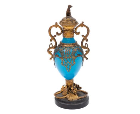 A Continental blue glass and gilt-metal mounted scent bottle: with seated dog finial, s-shaped handles, the black marble base