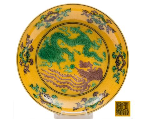 A small Chinese yellow ground phoenix and dragon dish: incised and painted in green and aubergine with a dragon and phoenix a