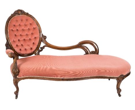 A Victorian carved walnut chaise longue:, the open scroll three quarter back with oval upholstered button down panel with cab