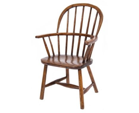 A child's early 19th Century ash and elm stick back Windsor elbow chair:, with a shaped solid seat on turned splayed legs, un