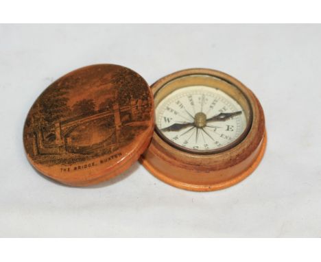 		A Maucheline ware box containing a compass, the cover with a view of the Bridge, Buxton. 1 ¾' diam.