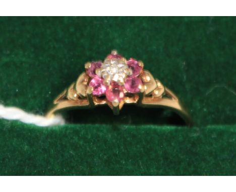 		A diamond and ruby cluster ring. In gold marked 9ct. Size M