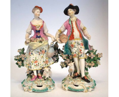 Pair of Derby figures circa 1770, modelled standing on scrolled bases with a floral bocage to the backs, a sheep and a dog at