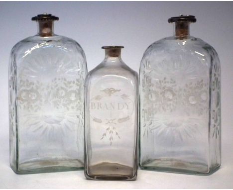 Two glass flask shape decanters, with rectangular bodies engraved with flora, silver hallmarked stoppers, and rims, also a Br