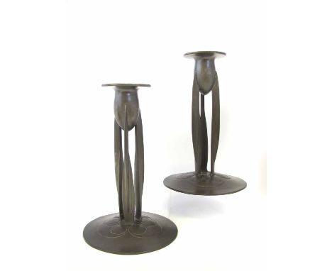 A pair of Archibald Knox for Tudric pewter candlesticks, model 0223, the oval sockets raised on three fin shaped supports on 