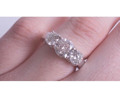 A fine platinum diamond three stone ring, with a platinum plain polished shank and head with four claw settings, unhallmarked