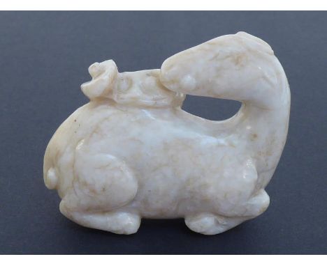 A Chinese jade carved figure of a recumbent deer, with head turned and mouth holding a branch of Lingzhi. Later Ming/ Earlier