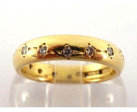 An 18 carat gold and diamond band, gypsy set with an undulating line of small brilliants, the band 4mm wide, the shank fully 