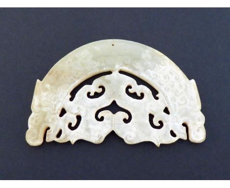 A Chinese archaic style carved jade pendant, crescent shaped formed as large dragons with a pair of smaller dragon in between