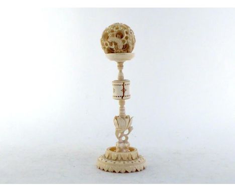 An early 20th century Chinese carved ivory puzzle ball with carved ivory stand holder, decorated with dragons on the ball and